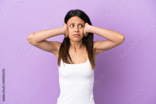 Young caucasian woman isolated on purple background frustrated and covering ears