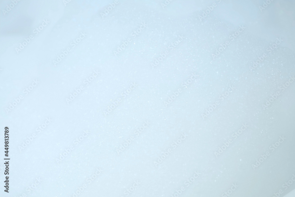 Obraz premium White bubbled foam in bathroom on blue tile background. Preparing to the bathing. Relaxed bath for people. Texture, background for video.