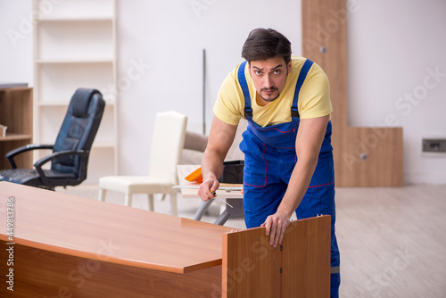 Young male carpenter repairing desk in the office