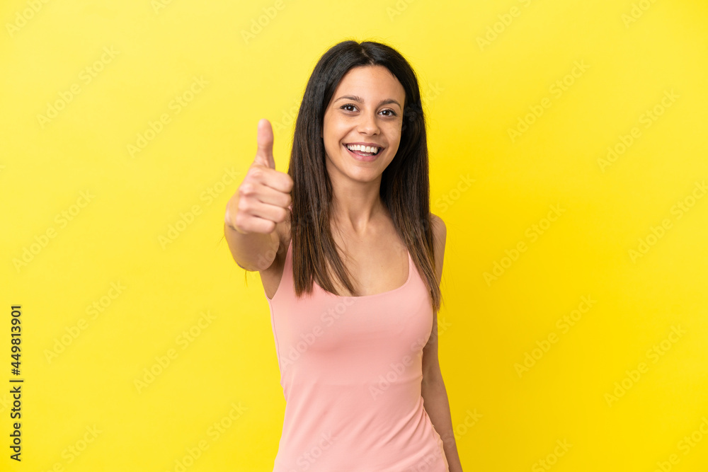 Young caucasian woman isolated on yellow background with thumbs up because something good has happened Young caucasian woman isolated on yellow background with thumbs up because something good has happened