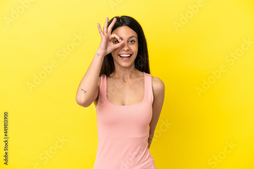 Young caucasian woman isolated on yellow background showing ok sign with fingers