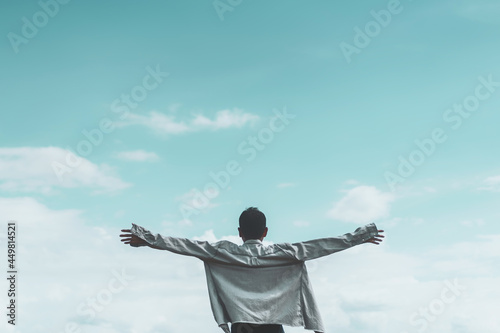 Copy space of man rising hands on blue sky white clouds abstract background. Freedom feel good and travel adventure concept.