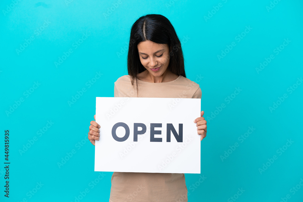Young woman over isolated background holding a placard with text OPEN Young woman over isolated background holding a placard with text OPEN