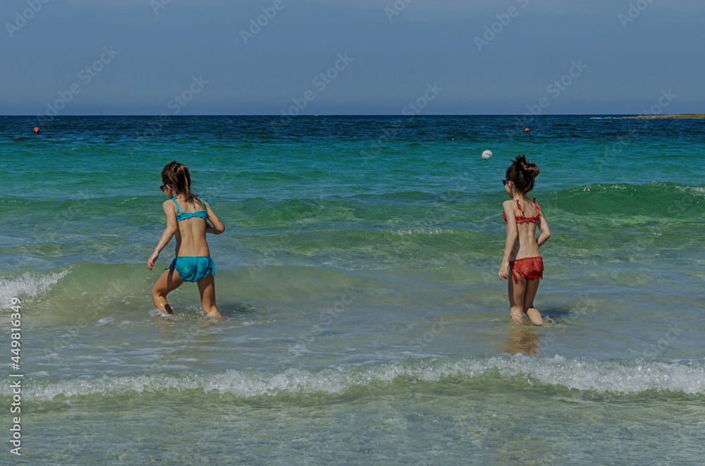 Bambine di sette anni che giocano in acqua al mare.