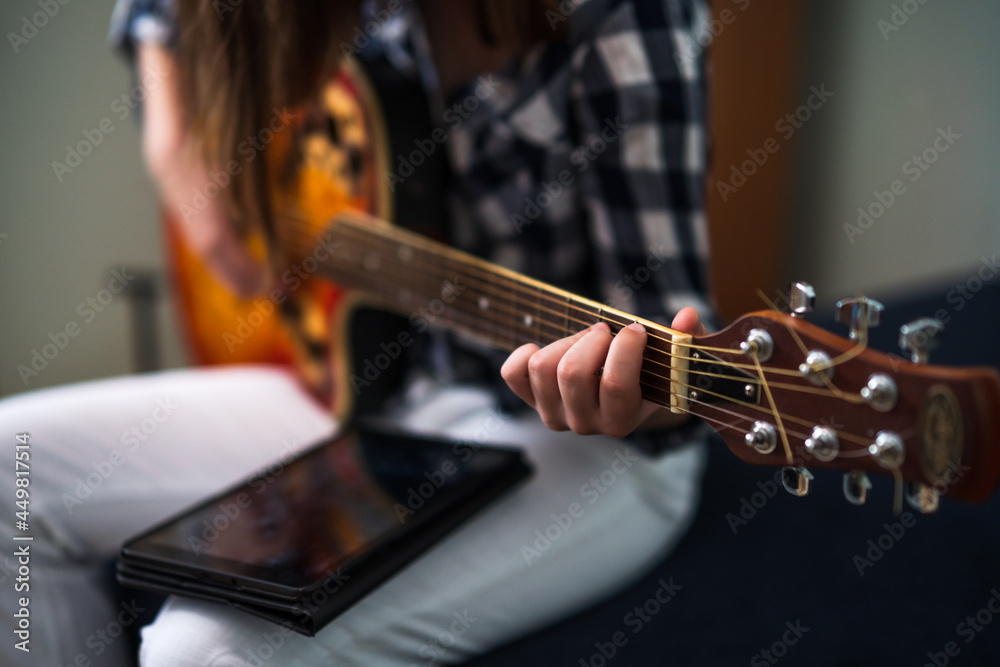 Fototapeta premium Teenage girl is playing guitar at home.
