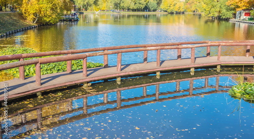 Fototapeta Naklejka Na Ścianę i Meble -  Autumn landscape with wooden bridge over the pond in the park