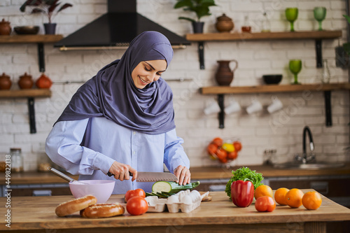 Young Arabian woman cutting a zucchini and smiling