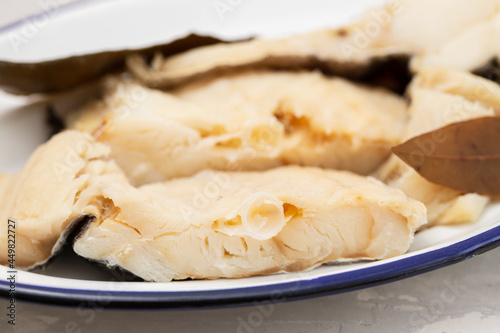boiled cod fish with bay leaf on white dish