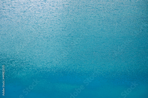 The surface is blue water with ripples from the light wind and reflection. Abstract water perfect background.