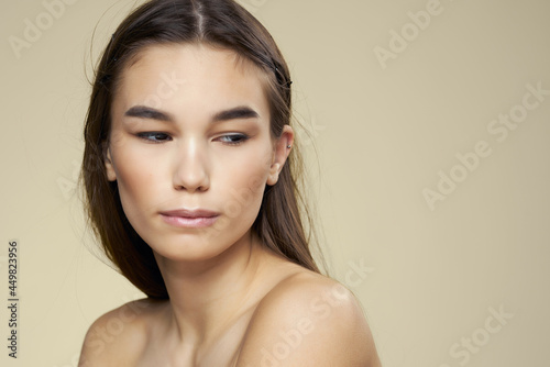 pretty woman with bare shoulders skin care beige background