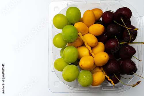 Colorful fruits of yellow raw of date palm fresh,green graps and cherry with water droplets are sweet healthy fruit in food box and  isolated on white background. photo