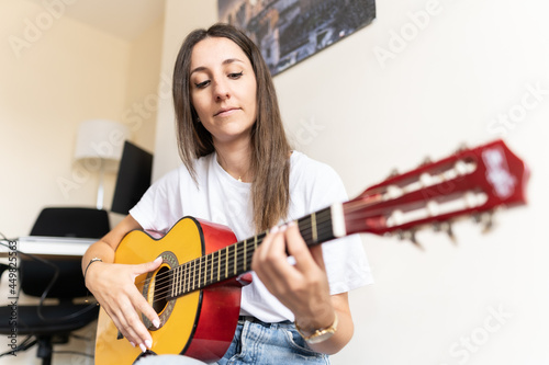 Photography Attractive young female playing the guitar at home while learning new chords and