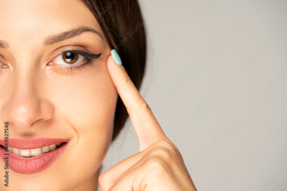 Young smiling woman tightening her face skin with her fingers Young smiling woman tightening her face skin with her fingers