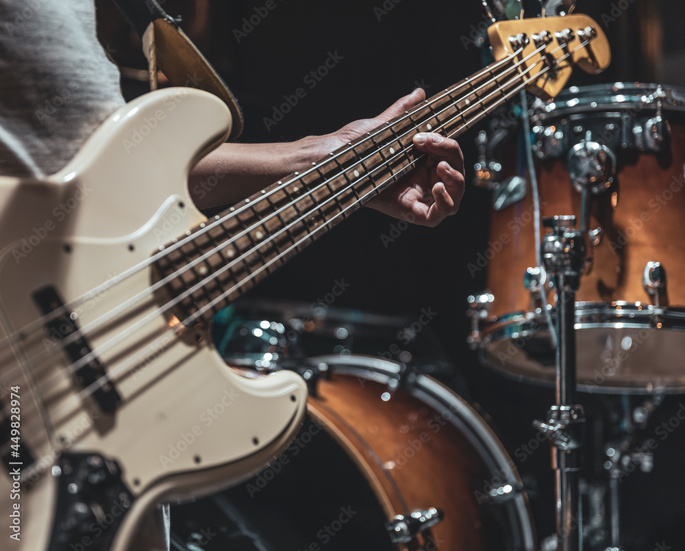 Fototapeta premium A man plays the bass guitar on a blurred background with bokeh.