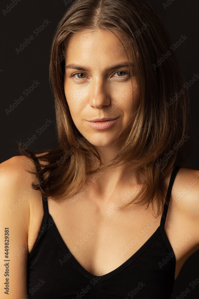 Close-up portrait of young beautiful tanned pretty woman without makeup isolated over black studio background. Natural beauty, facial emotion concept. Close-up portrait of young beautiful tanned pretty woman without makeup isolated over black studio background. Natural beauty, facial emotion concept.