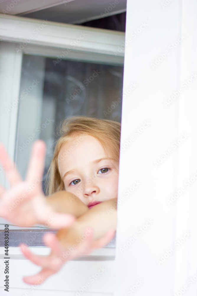 a girl in a pink dress looks out the window, child alone at home a girl in a pink dress looks out the window, child alone at home
