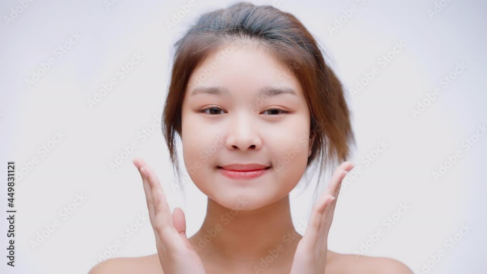 Beauty Asian woman face looking at the camera, isolated on white background. Beautiful female model with perfect clean fresh skin. Skincare treatment or cosmetic ads concept