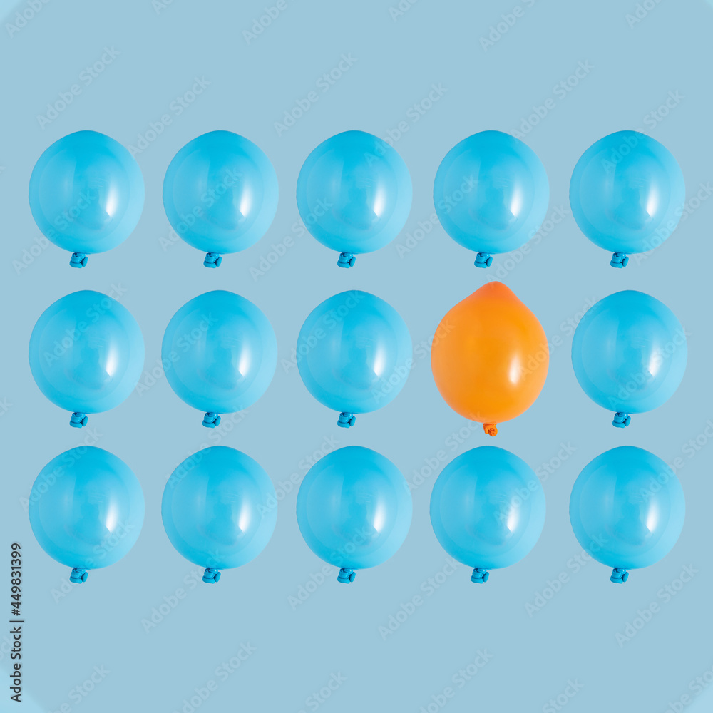 Pattern made of blue balloons on a light blue background with one orange balloon. Independence, individuality, individualism, creativity, uniqueness creative minimal concept.
