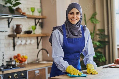 Portrait of an Arabian housewife cleaning a table in the kitchen photo