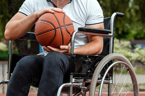 A man in a wheelchair plays basketball on the sports ground. The concept of a disabled person, a fulfilling life, a person with a disability, fitness, activity, cheerfulness