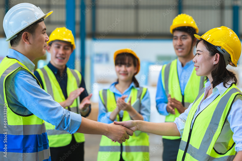 Factory employee of engineers, foreman, technicians and staff. Wear a mask, hard hat, and vest. shake hands to make a deal or celebrate success in the organization or warehouse. Teamwork concept. Factory employee of engineers, foreman, technicians and staff. Wear a mask, hard hat, and vest. shake hands to make a deal or celebrate success in the organization or warehouse. Teamwork concept.