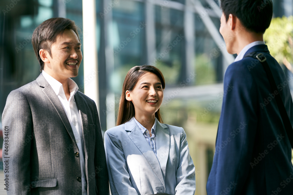 team of three asian business people chatting talking conversing outdoors on downtown street in modern city team of three asian business people chatting talking conversing outdoors on downtown street in modern city