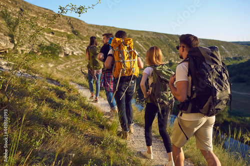 Group of men and women walk in a row along the trail during a walking tour of the mountains. Adventure, travel, tourism, hike and people concept. Camping season.