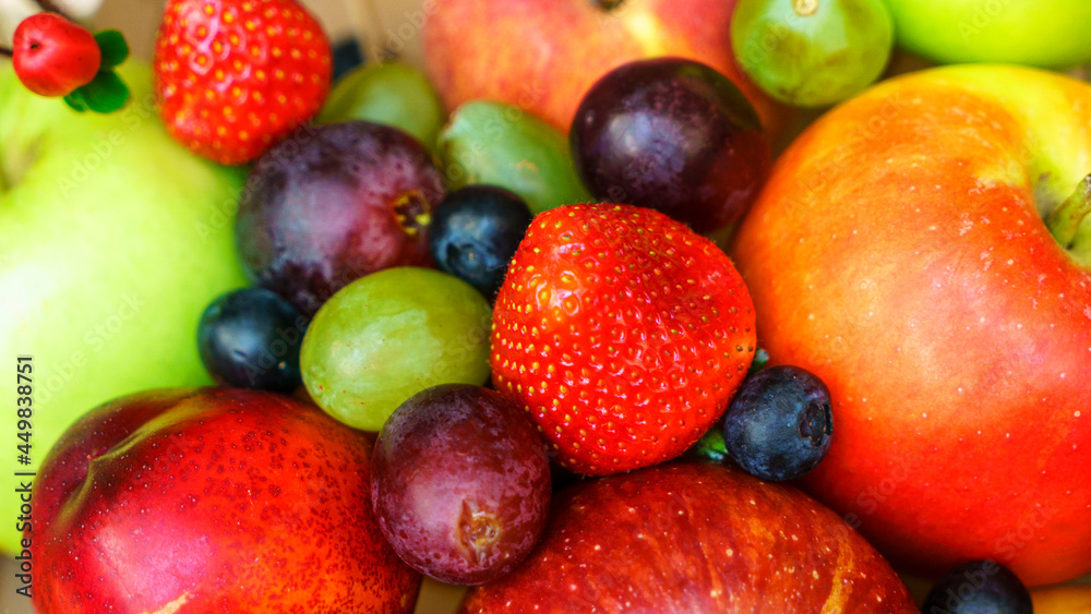 Summer fruit, berry assortment. Big apple, plum, apricot, grape and strawberry. Colorful berries in wooden crate on the table.