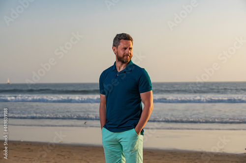 Outdoor portrait of handsome man posing at beach, in nice sunny day, wearing casual sorts classic shirt. Portrait of man on beach.
