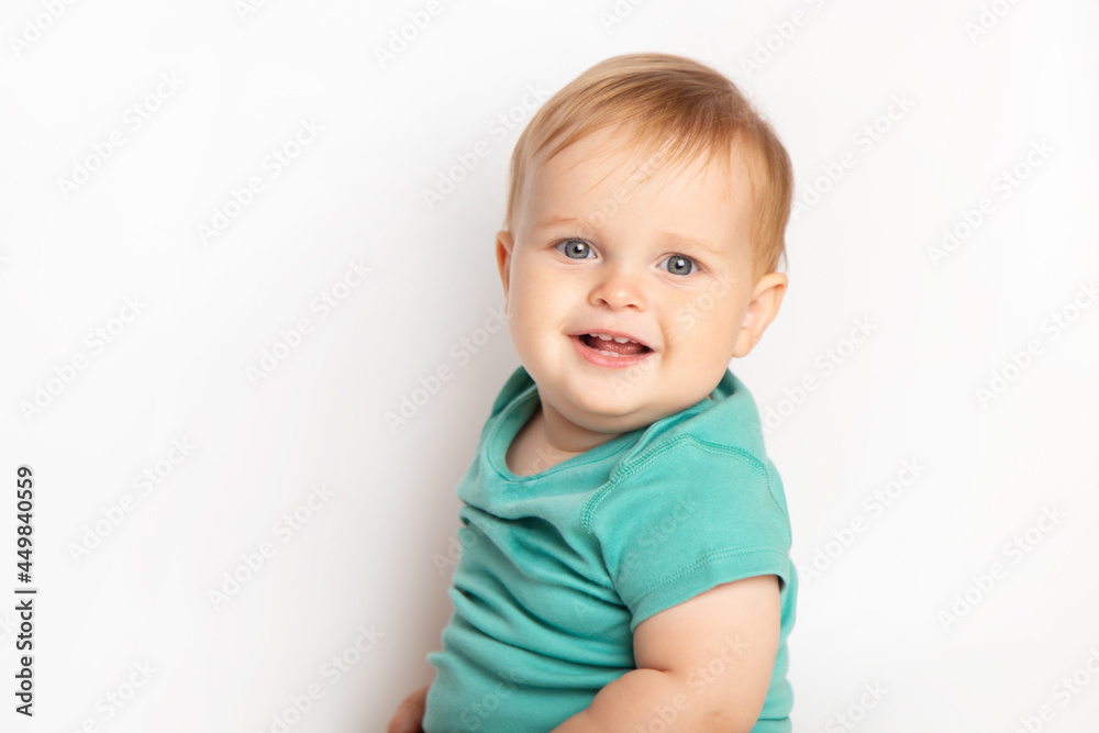 Infant child baby boy in green t-shirt laughs happy looking at the camera isolated on a white background. Childcare and upbringing concept. Infant child baby boy in green t-shirt laughs happy looking at the camera isolated on a white background. Childcare and upbringing concept.