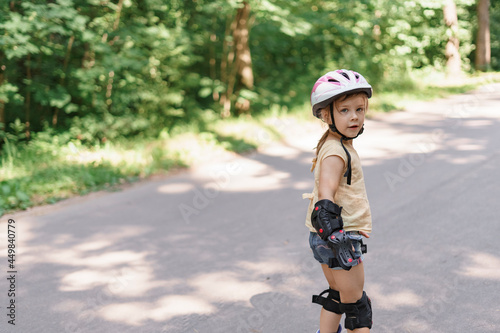 little girl learning to roller skate. baby in protective sportswear