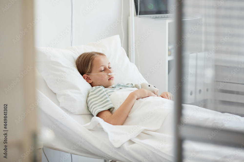 Side view portrait of little girl laying in hospital bed with oxygen support, copy space Side view portrait of little girl laying in hospital bed with oxygen support, copy space