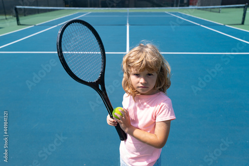 Child with tennis racket and ball on tennis court outdoor. Sport exercise for kids. Summer activities for children. Training for young kid © Volodymyr