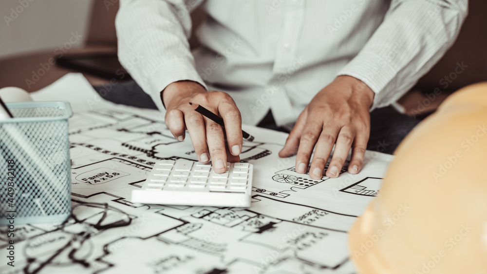 Male engineer or architect is pressing a calculator to calculate the building's structure and balance, Architects or engineers are designing buildings using calculator to calculate Male engineer or architect is pressing a calculator to calculate the building's structure and balance, Architects or engineers are designing buildings using calculator to calculate
