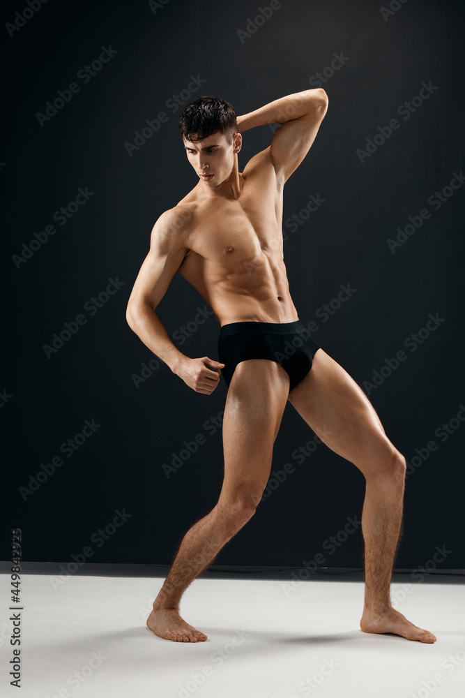 man with a pumped up muscular body in black panties posing against a dark background man with a pumped up muscular body in black panties posing against a dark background
