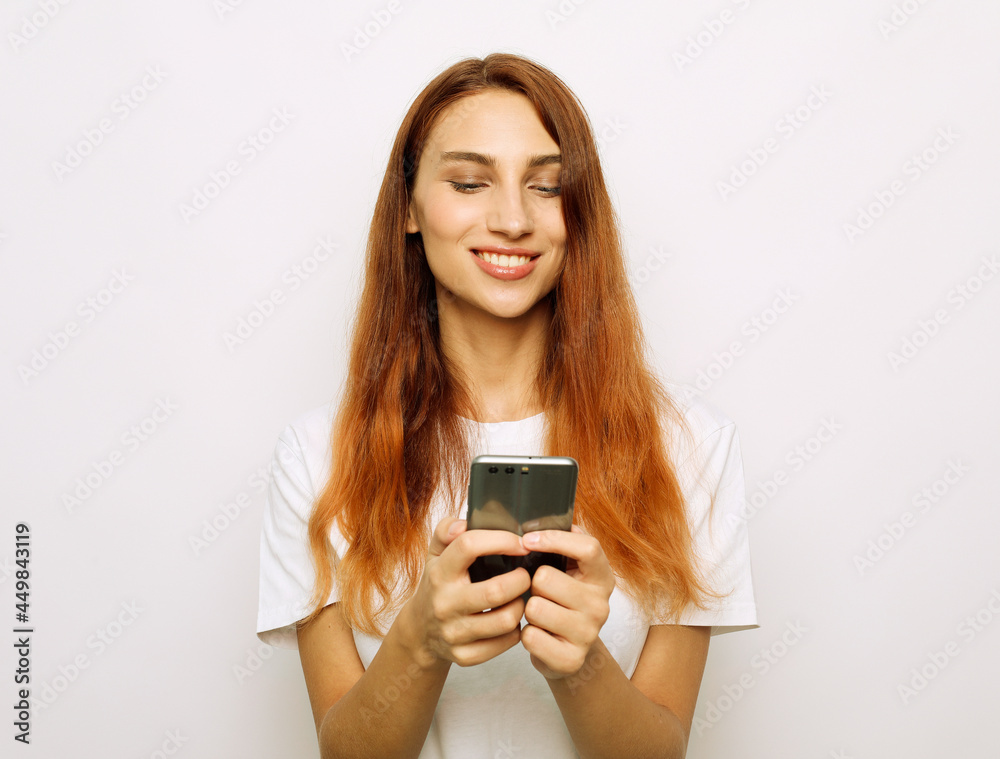Photo of cheerful beautiful young red-haired woman chatting by mobile phone Photo of cheerful beautiful young red-haired woman chatting by mobile phone
