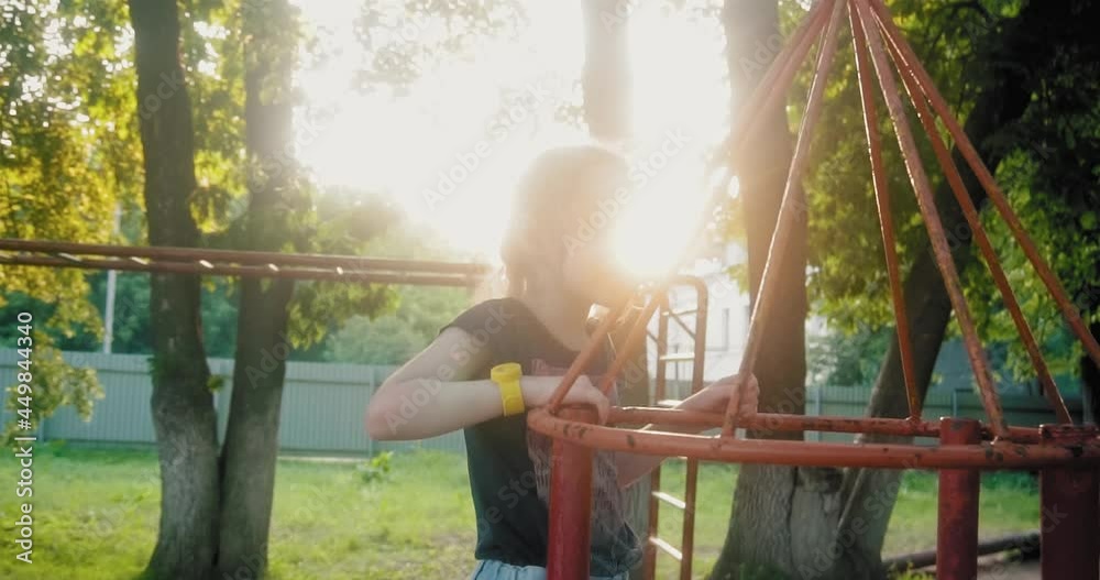 The girl child plays on the playground, a bright sunny day for walks in the fresh air. The rays of the sun shine through the trees. Children's joy and laughter. The girl child plays on the playground, a bright sunny day for walks in the fresh air. The rays of the sun shine through the trees. Children's joy and laughter.