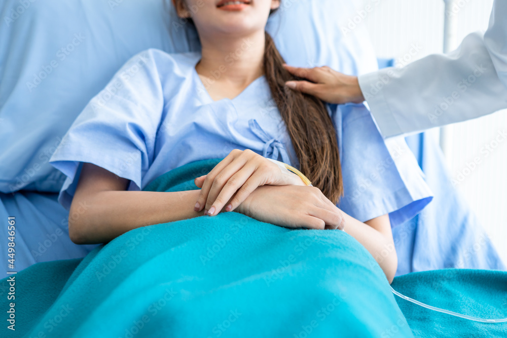 asian young female doctor care hold the shoulder with young female patient carefully for encouragement and hope on bed at nursing hospital ward in hospital background.