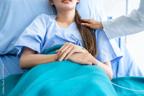 Obraz na płótnie asian young female doctor care hold the shoulder with young female patient carefully for encouragement and hope on bed at nursing hospital ward in hospital background. w salonie