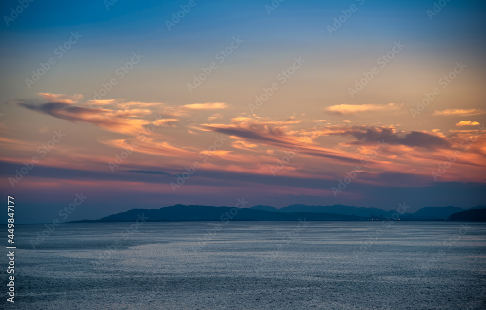Beautiful cloudscape and dramatic sunset over mountain and sea.