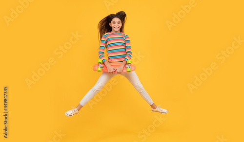 skateboarding. happy child jump with penny board. teen girl on yellow background.