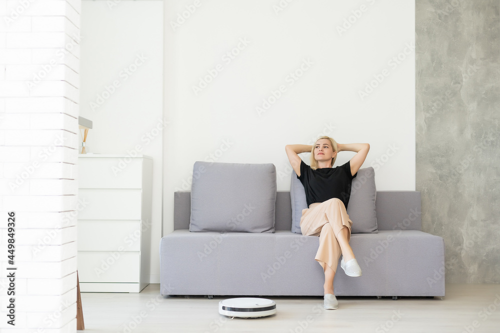 Young woman using automatic vacuum cleaner to clean the floor, controling machine housework robot Young woman using automatic vacuum cleaner to clean the floor, controling machine housework robot