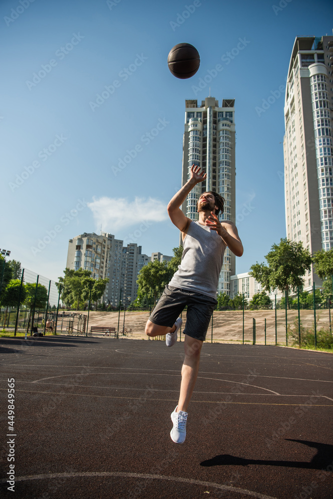 Player jumping and throwing basketball ball on court at daytime