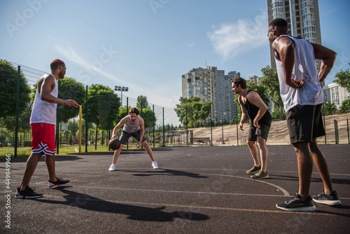 Man playing basketball with interracial friends on playground