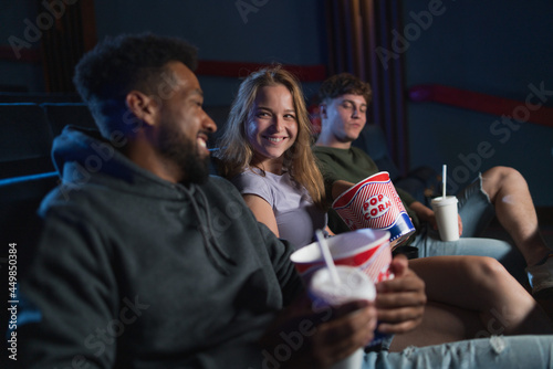 Cheerful young couple with popcorn in the cinema  talking.