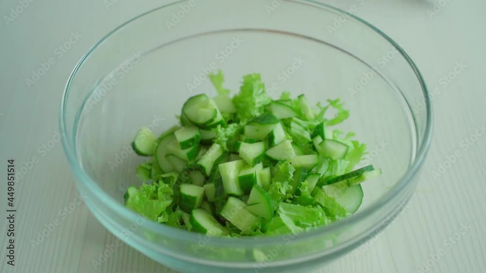 The chef puts the cucumbers off the cutting board into the salad The chef puts the cucumbers off the cutting board into the salad