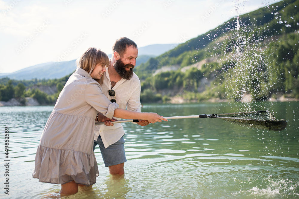 Happy preteen girl and father with fishing net on summer holiday by lake. Happy preteen girl and father with fishing net on summer holiday by lake.