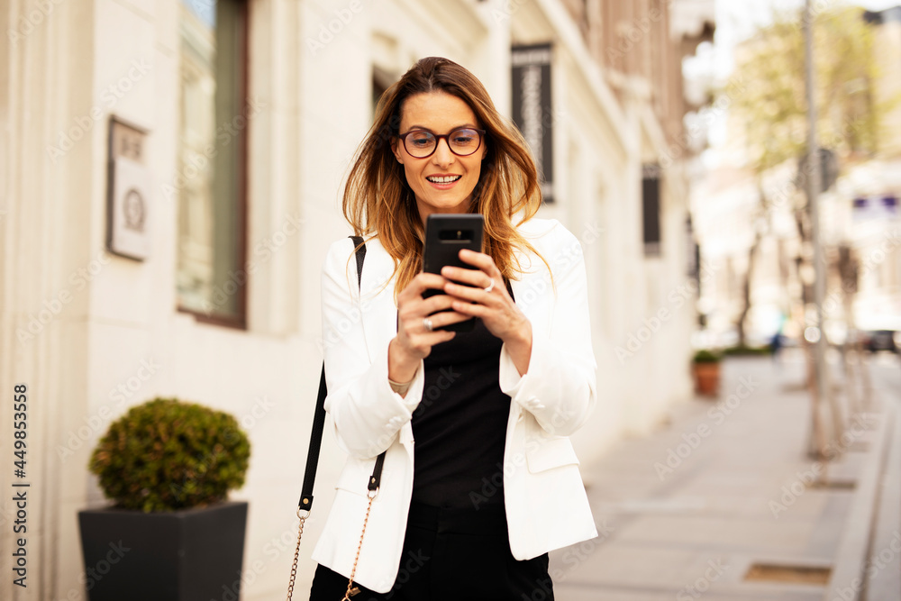Beautiful young businesswoman outdoors. Portrait of happy woman using the phone