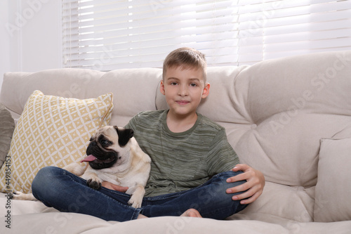 Boy with his cute pug on sofa at home © New Africa