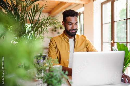 Young man with laptop and coffee working indoors, home office concept. photo